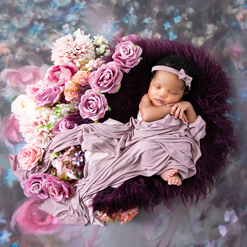 Newborn photography session of a baby girl wrapped in a soft pink blanket with toes peeking out